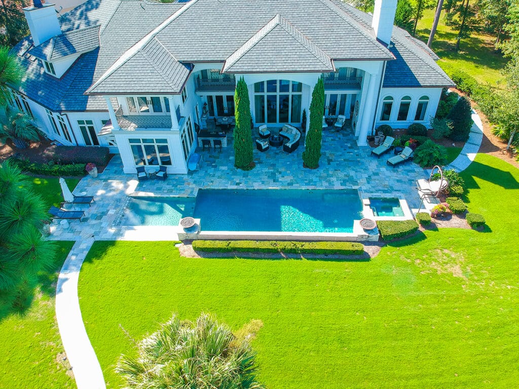 Aerial backyard pool with modern home and manicured lawn
