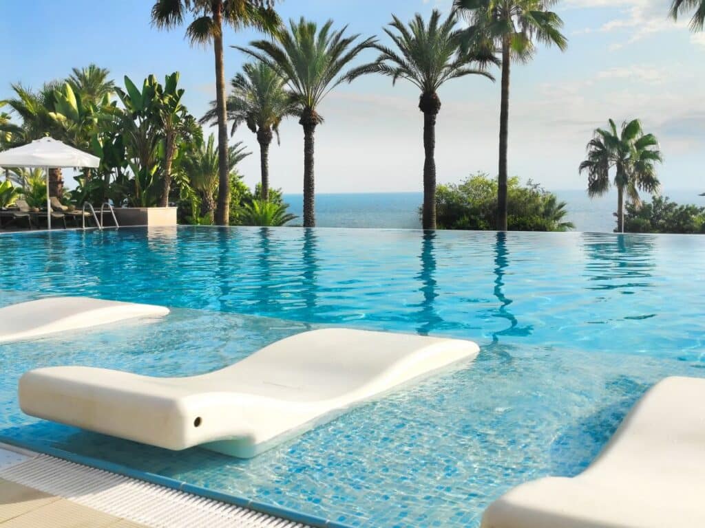 Luxury resort-style infinity pool with palm trees and ocean view