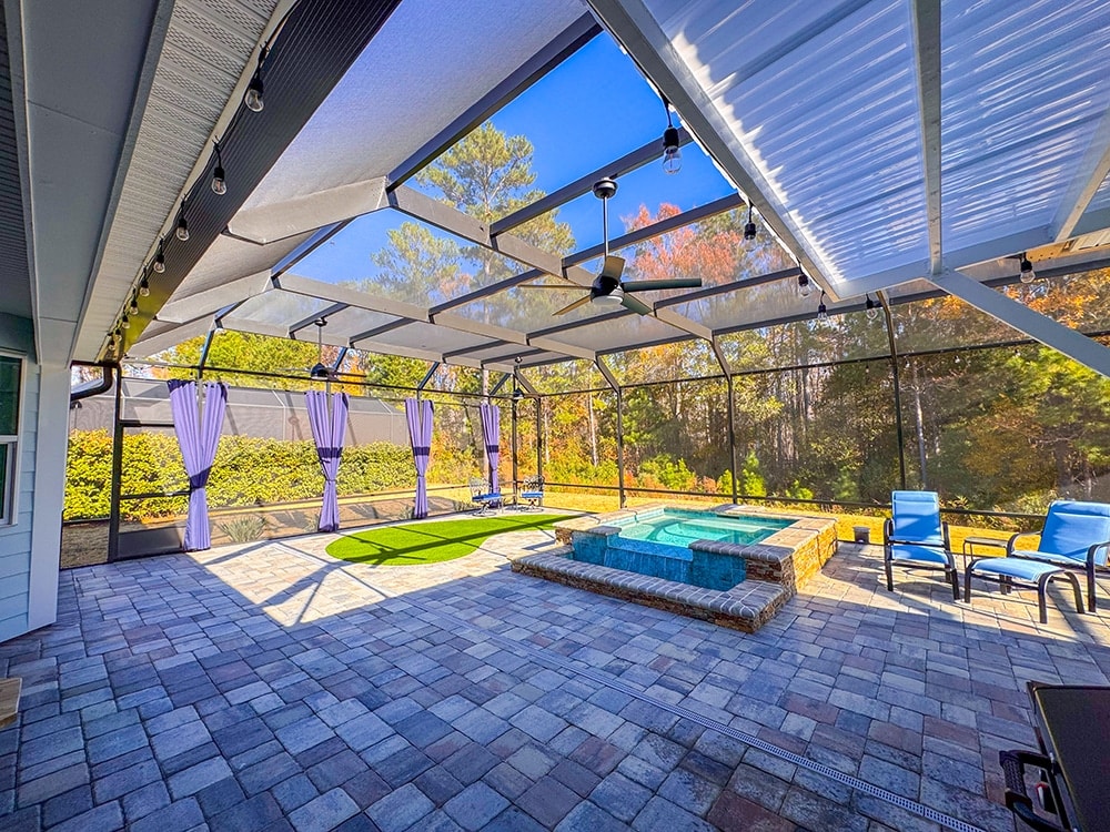 Artificial putting green next to a screened swimming pool and spa in a custom outdoor living area.